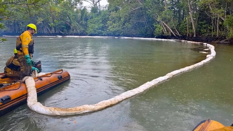 Lực lượng xử lý môi trường đang khoanh vùng dầu loang. 
