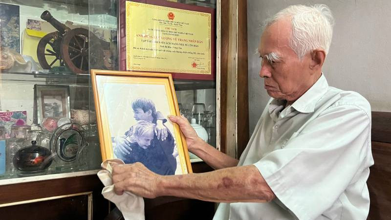 Ông Lê Văn Thức bên bức ảnh nổi tiếng "Ngày hội ngộ". (Ảnh: HOÀNG TRUNG)