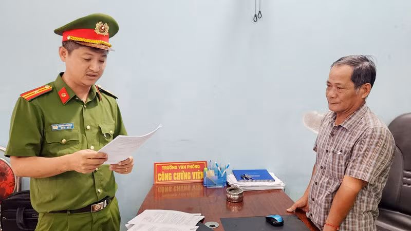 Điều tra viên đọc lệnh bắt tạm giam ông Trần Thiện Thi. (Ảnh: Văn Vũ)