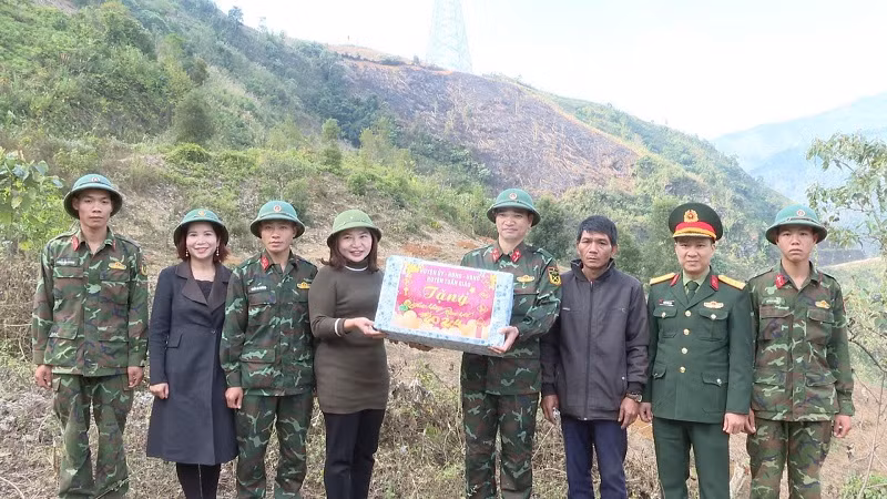 Đồng chí Phạm Thị Tuyên, Phó Chủ tịch Ủy ban nhân dân huyện Tuần Giáo tặng quà, động viên cán bộ, chiến sĩ Trung đoàn 82 đang thực hiện nhiệm vụ giúp người nghèo ở huyện Tuần Giáo đào hố trồng cây mắc-ca.