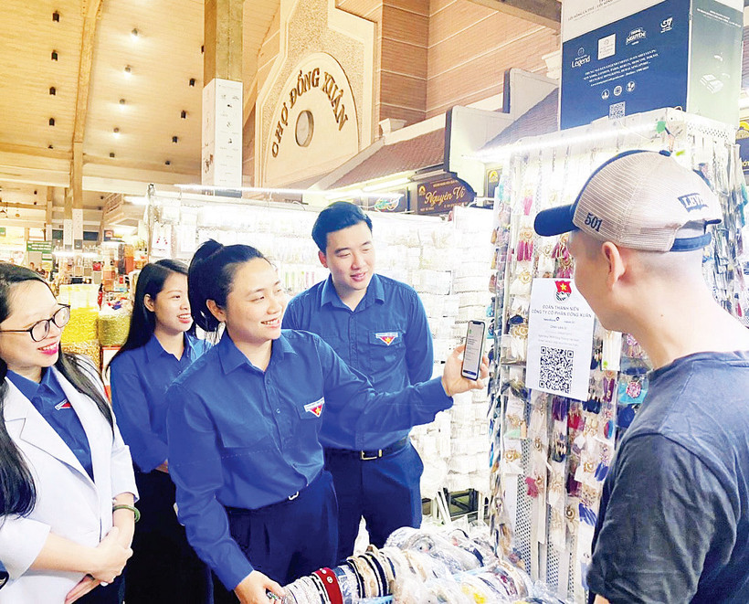 Đoàn viên, thanh niên quận Hoàn Kiếm hướng dẫn các hộ kinh doanh, người mua hàng tại chợ Đồng Xuân sử dụng mã QR khi thanh toán.
