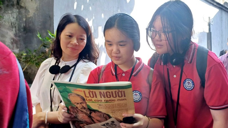 Cô giáo và học sinh trường THCS Chu Văn An (Tây Hồ, Hà Nội) đọc Báo Nhân Dân trong không gian Di tích Nhà tù Hỏa Lò.