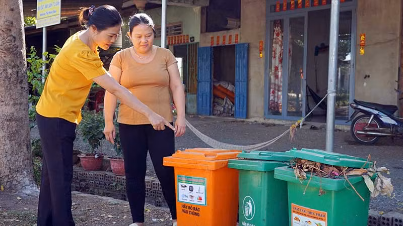 Cán bộ Hội Liên hiệp Phụ nữ xã Lang Minh, huyện Xuân Lộc, tỉnh Đồng Nai hướng dẫn người dân phân loại rác tại nguồn. (Ảnh MẠNH THÌN)