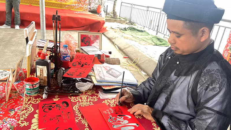 Anh Trần Hậu Thao viết chữ thư pháp tại khu di tích Đền Ông Hoàng Mười (Nghệ An).