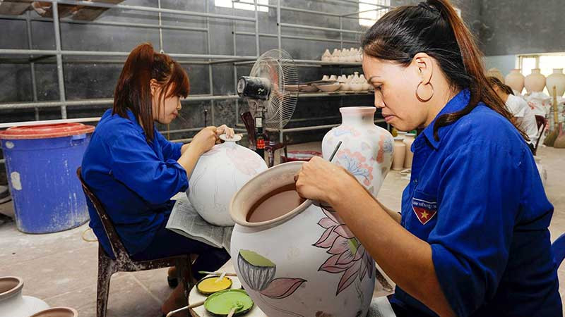 Vẽ hoa văn lên sản phẩm tại làng gốm Bát Tràng, Hà Nội. (Ảnh TUỆ NGHI)