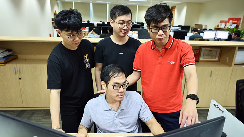 Nguyễn Tuấn Anh (áo đỏ) trao đổi nghiệp vụ với đồng nghiệp tại nhiệm sở. 