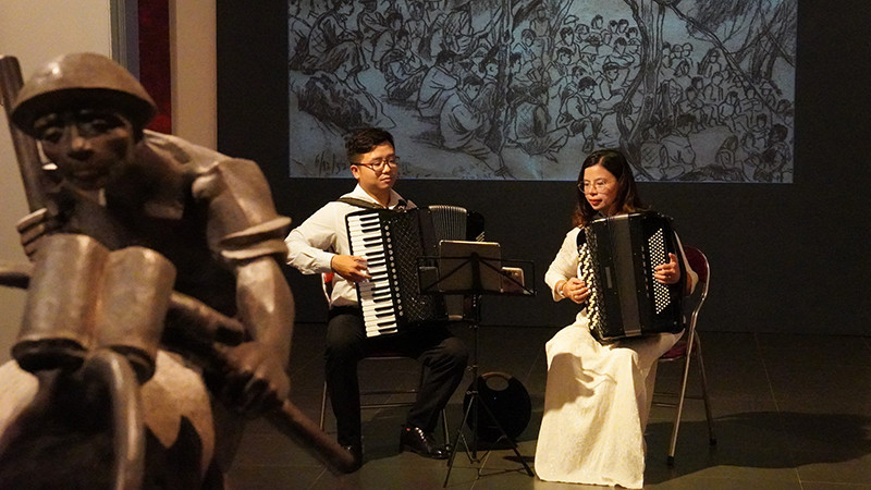 Hai nghệ sĩ accordion Nguyễn Quỳnh Chi và Vũ Việt Hưng biểu diễn trong không gian trưng bày các tác phẩm mỹ thuật về Chiến dịch Điện Biên Phủ tại Bảo tàng Mỹ thuật Việt Nam. (Ảnh: THANH BÌNH) 