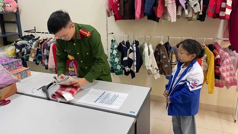 Gấp áo ấm tặng trẻ nhỏ đến làm thẻ căn cước. (Ảnh: HƯƠNG LAN).