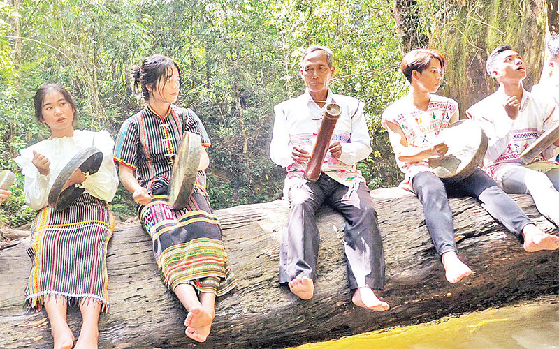 Già K’Vệ hướng dẫn các bạn trẻ cách chơi đàn ống tre. 