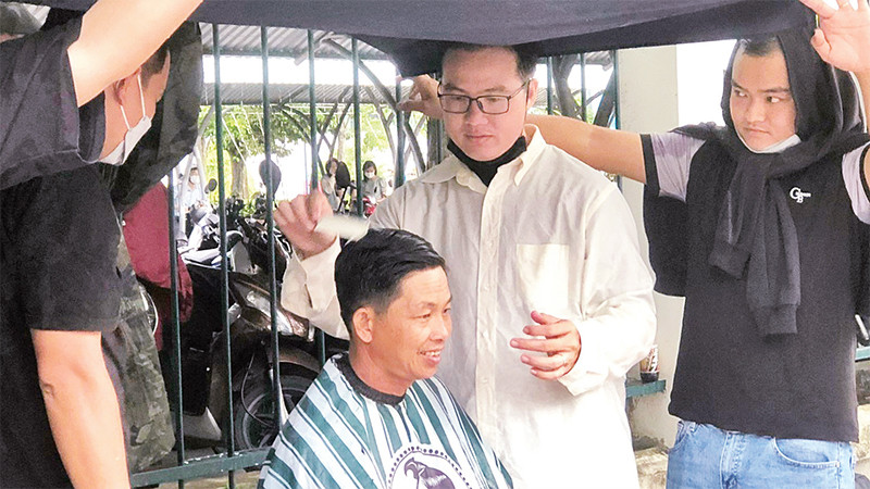 Anh Nguyễn Xuân Hiếu (áo trắng) cùng nhóm bạn trẻ cắt tóc miễn phí cho người dân.