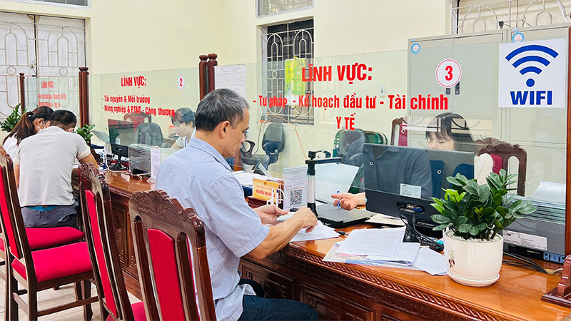 Cán bộ bộ phận một cửa huyện Ba Vì hỗ trợ người dân đến làm thủ tục hành chính. 
