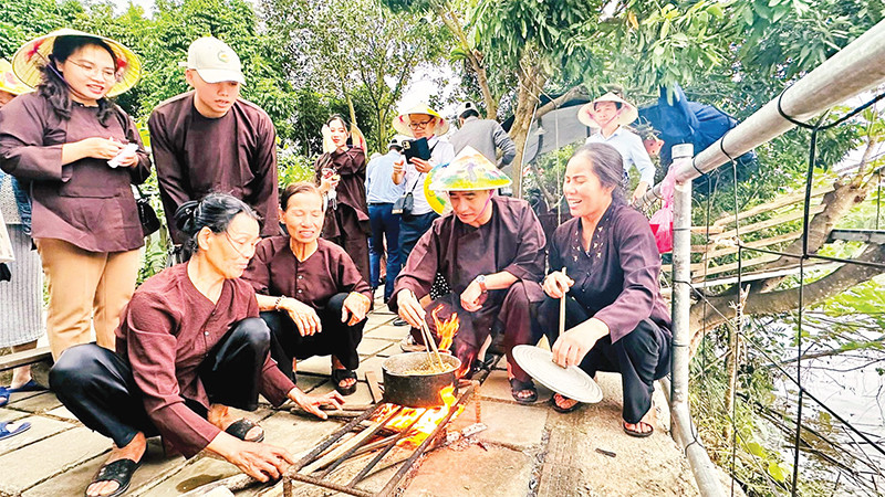 Du khách tìm hiểu các công đoạn làm bánh đúc truyền thống tại Giang Biên, quận Long Biên, TP Hà Nội. (Ảnh LINH TÂM) 