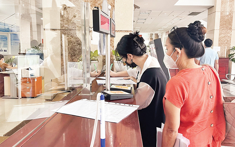 Cán bộ Cục Thuế thành phố hướng dẫn người dân kê khai các thủ tục nộp thuế. 