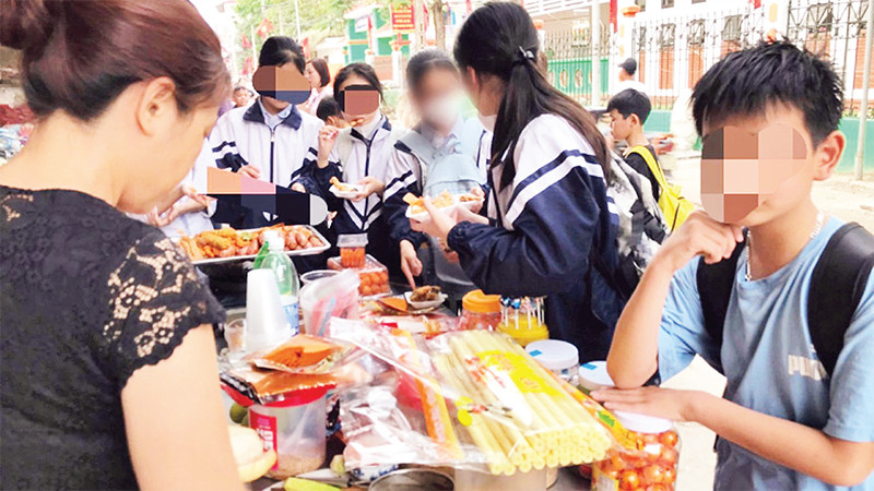 Hàng quà ăn vặt cho học sinh xuất hiện ở nhiều cổng trường học. (Ảnh TUẤN ANH) 
