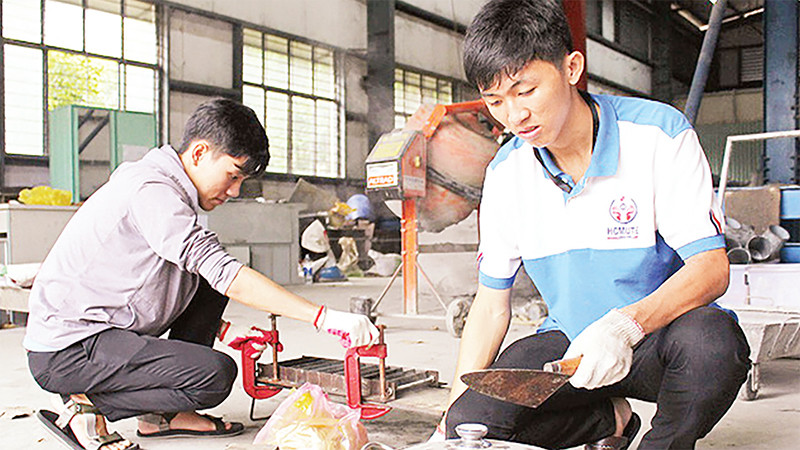 Từ nhiều thí nghiệm, Phạm Mạnh Ðình (bên phải) cùng cộng sự nghiên cứu thành công gạch tái chế từ rác thải nhựa. 