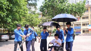 Tình nguyện viên tại điểm thi Trường THPT Nhân Chính hỗ trợ thí sinh bị gãy chân lên phòng thi.