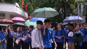 Tình nguyện viên hỗ trợ che ô cho thí sinh sau khi hoàn thành bài thi.
