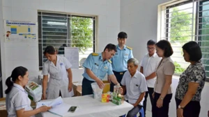 Đại diện lãnh đạo phường Tùng Thiện và Học viện Phòng không-Không quân khám bệnh, cấp thuốc miễn phí cho người có công. 