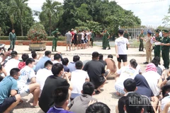 Lực lượng chức năng Việt Nam tiếp nhận các công dân liên quan tội phạm lừa đảo trực tuyến do phía Campuchia bàn giao tại khu vực cửa khẩu Mộc Bài. (Ảnh: ĐINH TRƯỜNG)