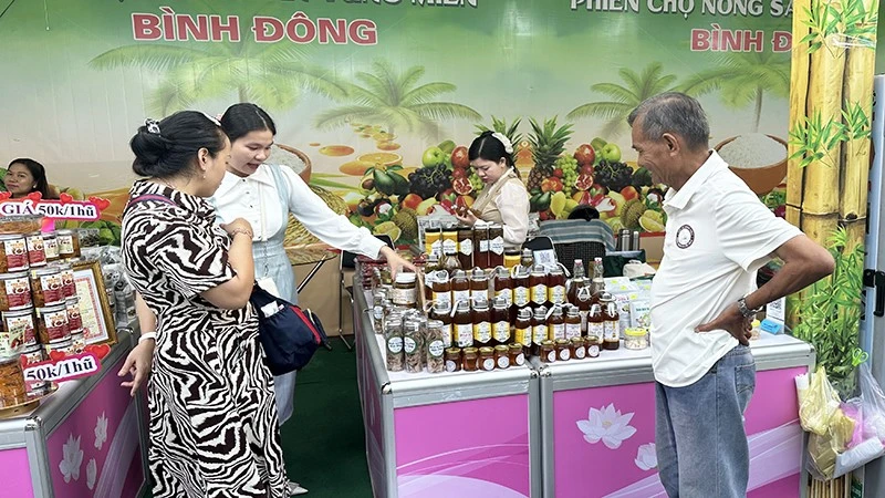 Người dân và khách tham quan tìm mua đặc sản tại một gian hàng của tỉnh Đồng Tháp trong phiên chợ.