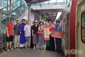 Du khách đi tàu di sản "tàu Hà Nội 5 cửa Ô" chụp ảnh lưu niệm cùng nhân viên phục vụ tàu.