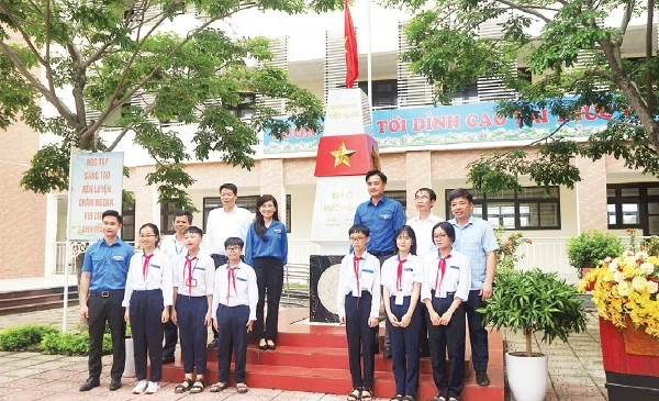 Đại biểu và các em học sinh chụp ảnh lưu niệm với Cột mốc chủ quyền biển đảo.
