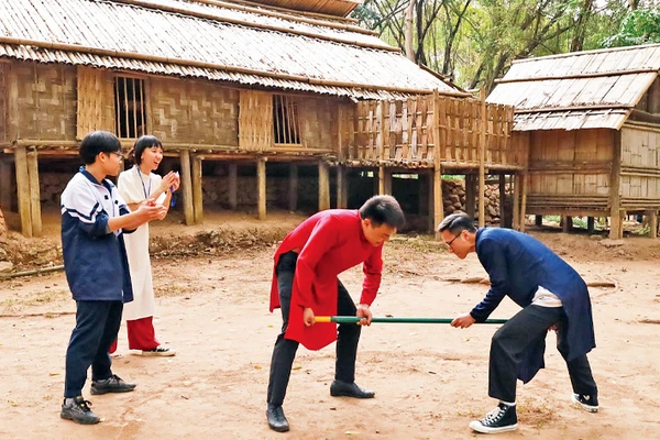 Khách tham quan tham gia trò chơi gậy của người dân tộc Mông. 