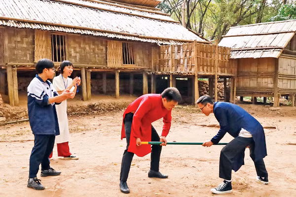 Khách tham quan tham gia trò chơi gậy của người dân tộc Mông. 