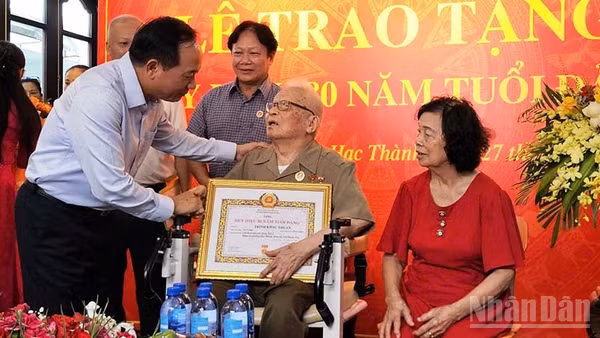 Đồng chí Trưởng Ban Tuyên giáo Trung ương trao Huy hiệu 80 năm tuổi Đảng cho cụ Trịnh Khắc Thuần. (Ảnh: MAI LUẬN)