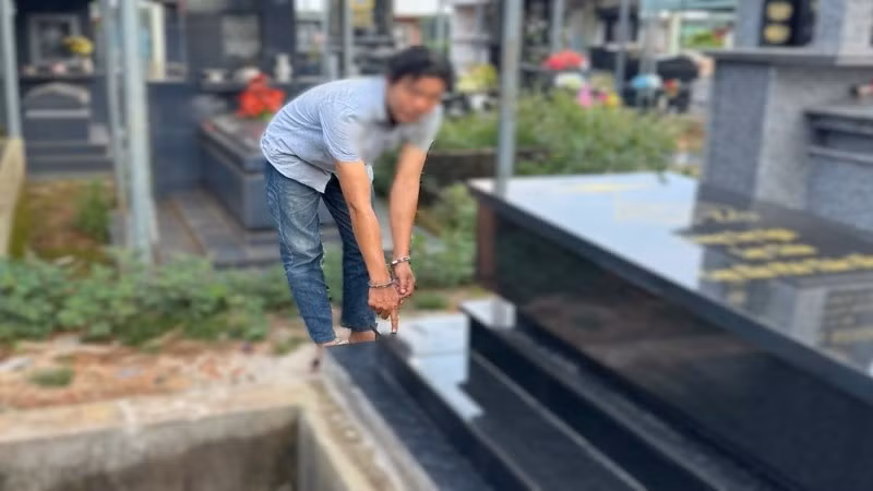 Đối tượng T.M.N tại ngôi mộ ông Phạm Hữu Tiến sau khi được gia đình sửa chữa lại.