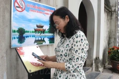 Du khách quét mã QR để trải nghiệm hành trình tham quan được số hóa tại Di tích đền Đô. (Ảnh: TTXVN)