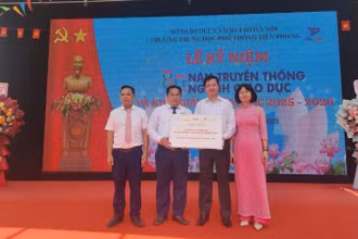 Đại diện Báo Nhân Dân trao biểu trưng 20 suất học bổng đến lãnh đạo Trường trung học phổ thông Tiền Phong. 