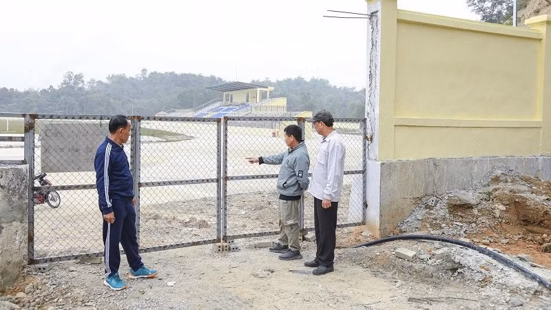 Ông Lò Văn Khăm (bên trái) cùng người dân trong bản Pú Tỉu 2 (phường Mường Thanh), chỉ cho phóng viên dấu tích con đường cũ về bản hiện là một góc trong sân vận động mới được đầu tư xây dựng hiện đại. 