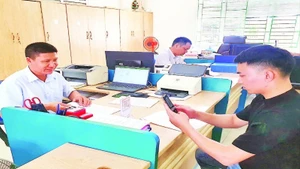 Cán bộ của Trung tâm Hành chính công huyện Hải Hà hướng dẫn người dân cài đặt ứng dụng thanh toán không dùng tiền mặt trên điện thoại thông minh.