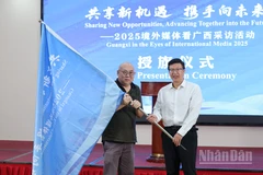 Ông Lê Phan, Chủ nhiệm Văn phòng Báo chí Chính quyền nhân dân khu tự trị dân tộc Choang Quảng Tây trao cờ cho đại diện truyền thông nước ngoài tham dự chương trình.