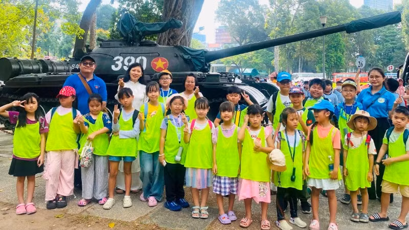 Chị Nguyên (áo dài trắng) cùng cộng sự đưa các em nhỏ đến thăm Dinh Độc Lập để tìm hiểu về lịch sử dân tộc. ẢNH: Tiệp Phạm