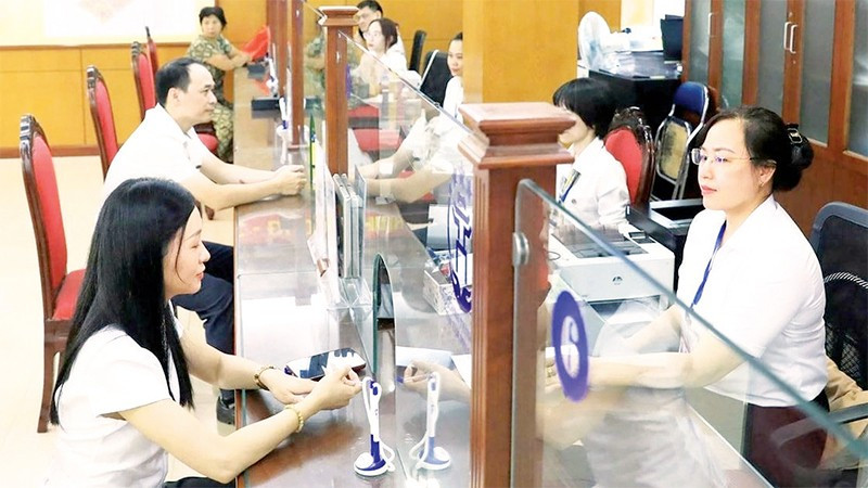 Giải quyết thủ tục hành chính cho người dân tại điểm phục vụ hành chính công phường Thanh Xuân. (Ảnh QUANG THÁI)