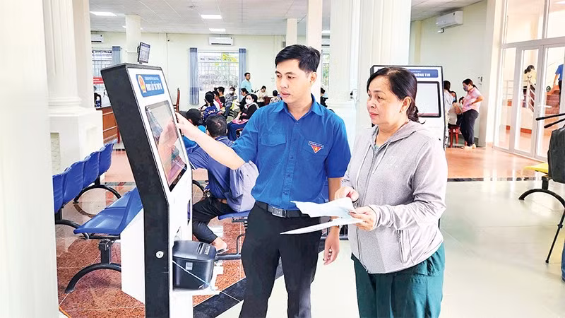 Cán bộ Trung tâm Phục vụ hành chính công phường Rạch Giá hướng dẫn người dân lựa chọn dịch vụ qua bảng điện tử.