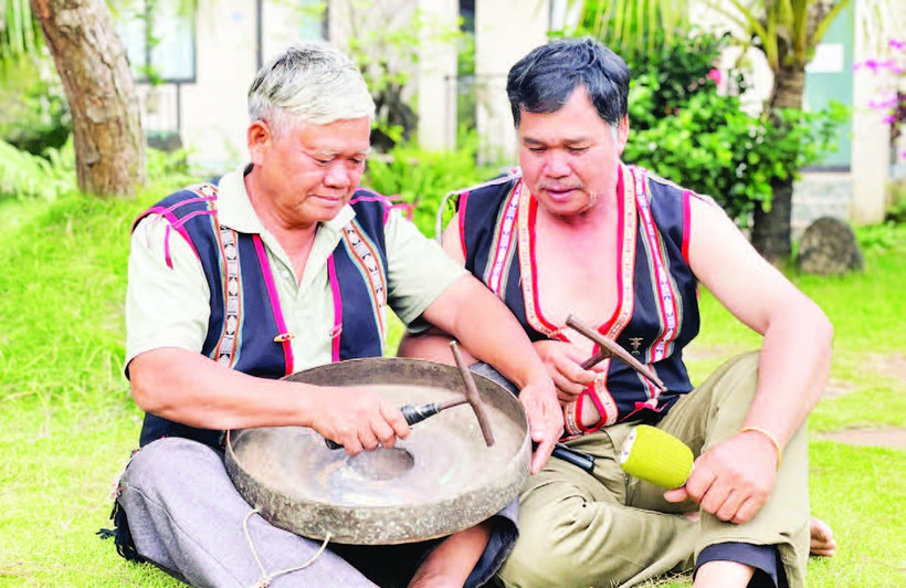Nghệ nhân Ưu tú Đinh Dôch (bên trái) hướng dẫn kỹ thuật chỉnh chiêng cho học viên. (Ảnh LAM NGUYÊN)