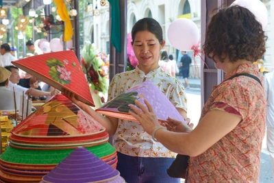 Du khách thích thú với những chiếc nón lá tại không gian làng nghề nón làng Chuông (huyện Thanh Oai, Hà Nội) trong khuôn khổ Festival Thu Hà Nội lần thứ 2 năm 2024. (Ảnh: THẾ ĐẠI)