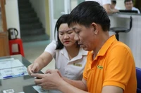 Cán bộ phường hướng dẫn người dân giải quyết thủ tục hành chính thông qua cổng dịch vụ công. (Ảnh: TTXVN)