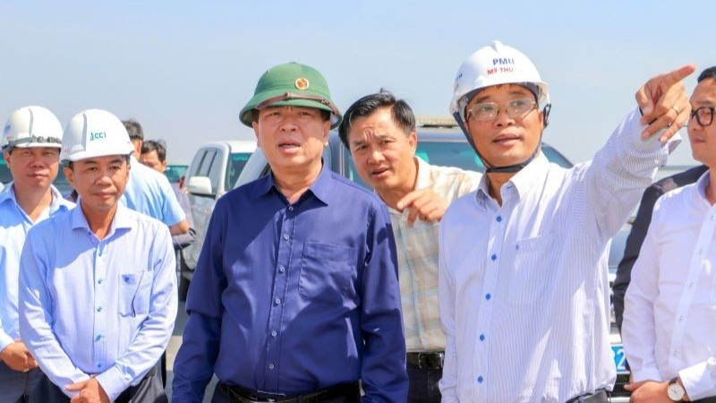 Lãnh đạo Ban Quản lý dự án Mỹ Thuận báo cáo tiến độ dự án cùng với Bộ trưởng Xây dựng Trần Hồng Minh (áo xanh đậm) tại hiện trường.