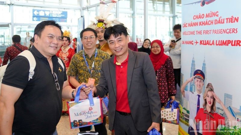 Ông Trần Hoàng Linh (phải), Giám đốc Văn phòng miền trung Vietjet đại diện hãng chào đón và tặng quà hành khách trên chuyến bay khai trương.