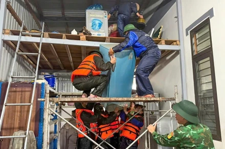 Lực lượng chức năng tỉnh Quảng Trị hỗ trợ người dân di chuyển tài sản lên nơi khô ráo. (Ảnh HIẾU MINH)