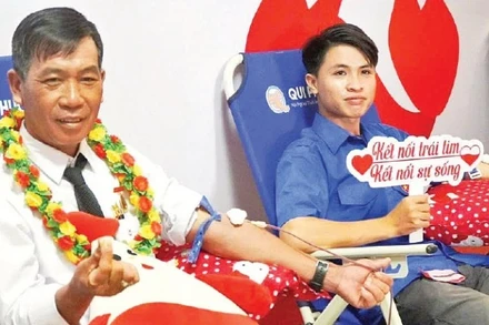 Ông Trần Minh Mến (bên trái) tham gia hiến máu tình nguyện. (Ảnh: Lê Minh)
