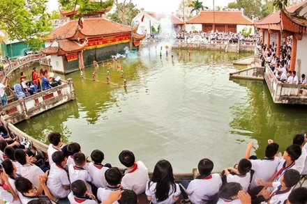 Các em học sinh xem trình diễn rối nước ở làng Thư Lâm, thành phố Hà Nội. (Ảnh: Báo Nhân Dân)