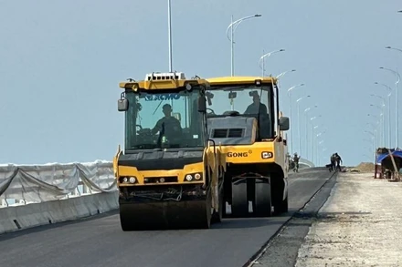 Thi công trải thảm bê-tông nhựa trên cây cầu vượt sông Hồng thuộc dự án đường bộ ven biển tỉnh Hưng Yên.