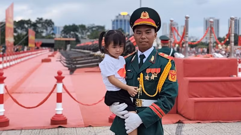 Hình ảnh chiến sĩ pháo binh Đỗ Kim Vũ bế cháu gái đến cổ vũ trong chương trình Tổng hợp luyện diễu binh, diễu hành lần 2. (Ảnh: VĂN THỊNH)