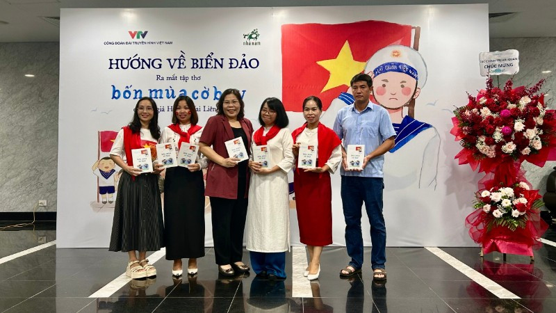 Nhà thơ, nhà báo Huỳnh Mai Liên (mặc áo dài trắng) trong buổi ra mắt tập thơ "Bốn mùa cờ bay". 