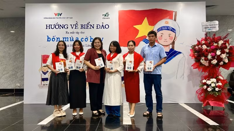 Nhà thơ, nhà báo Huỳnh Mai Liên (mặc áo dài trắng) trong buổi ra mắt tập thơ "Bốn mùa cờ bay". 